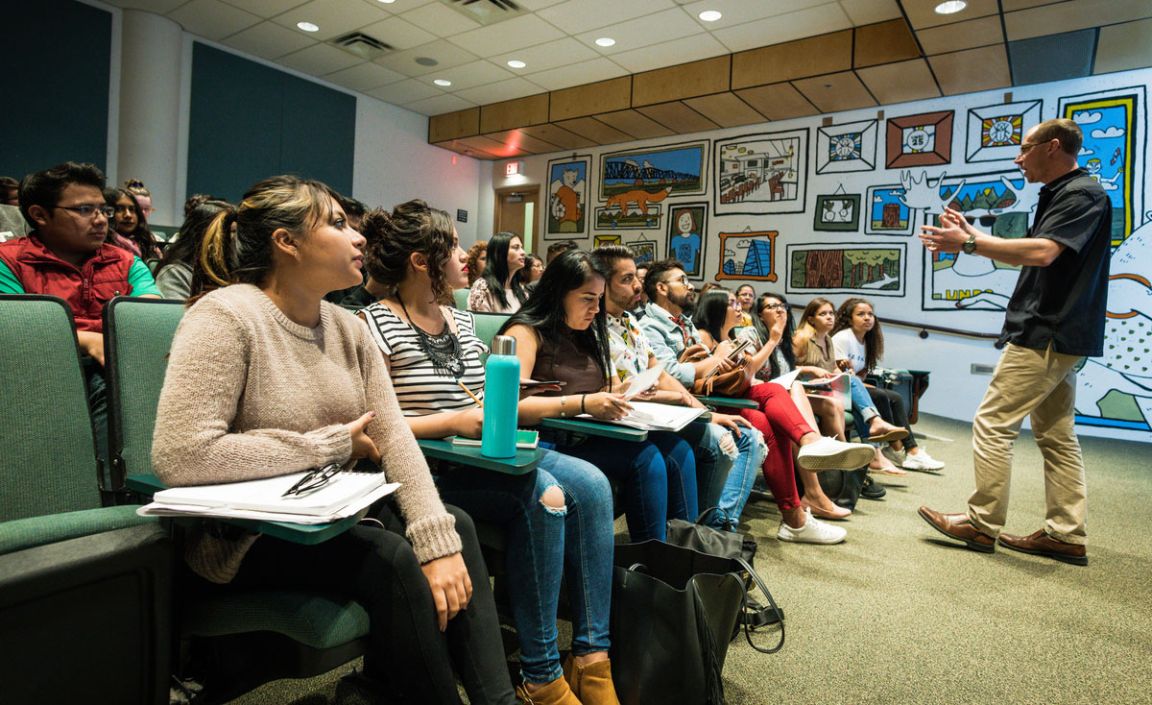 Students in class listening to a teacher presenting