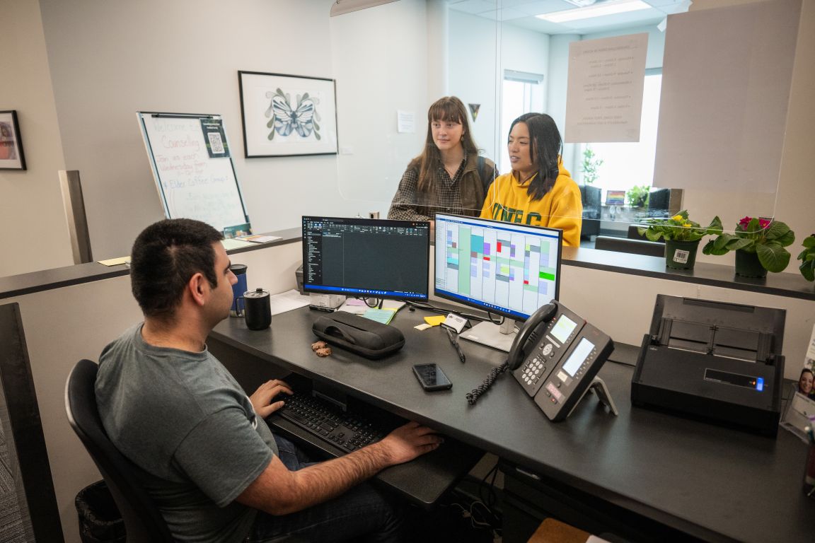 UNBC staff and students talking at a reception desk