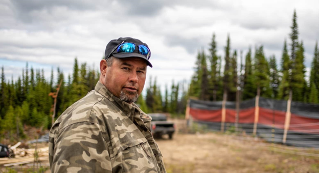 Roland Willson in front of trees and a truck