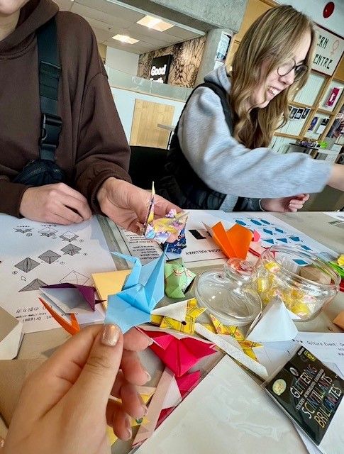 A crane folded by someone at the table, with other origami items in the background