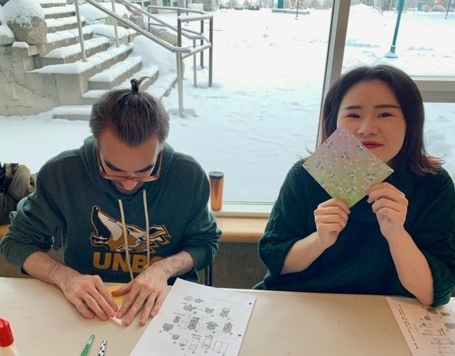 Two students following origami folding instructions