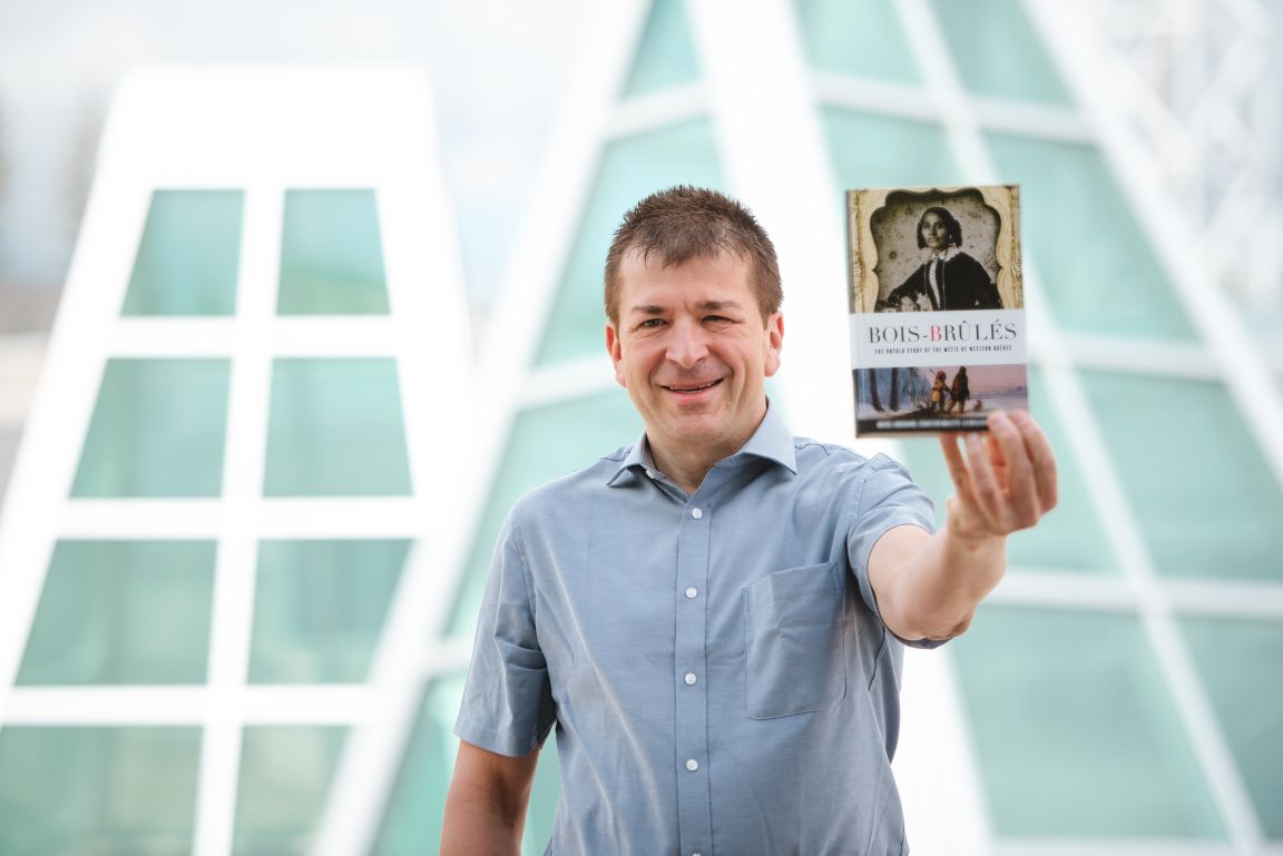 Anthropology Professor Dr. Michel Bouchard holds a copy of his book