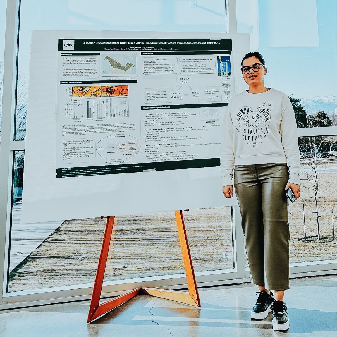 A student stands next to their research poster 