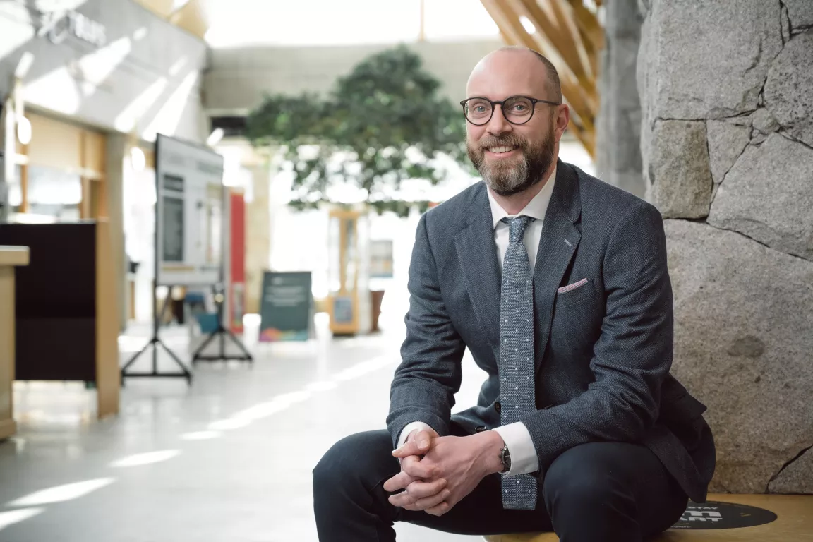 Dr. Kriston Rennie sits on a bench on TELUS Student Street.