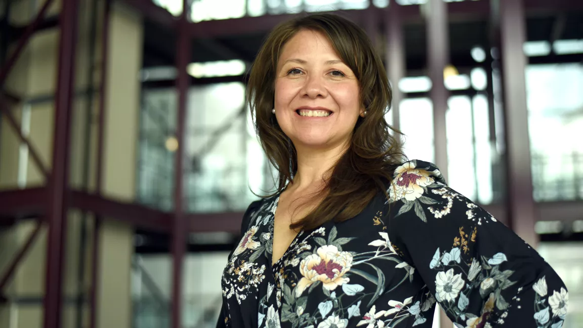 Person wearing floral blouse poses for photo in building atrium