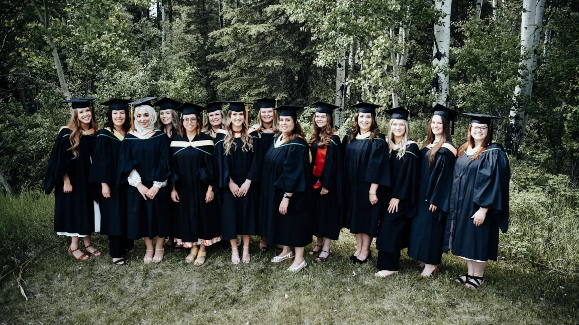 Group photo of all graduates from the Northeast campus in Fort St John. Graduates are wearing cap and gowns, photo is outside.