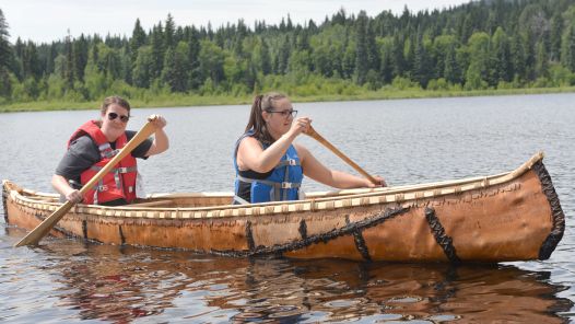 Students Nicole Hoffman and Jacey Wolfe paddle a birch bark canoe