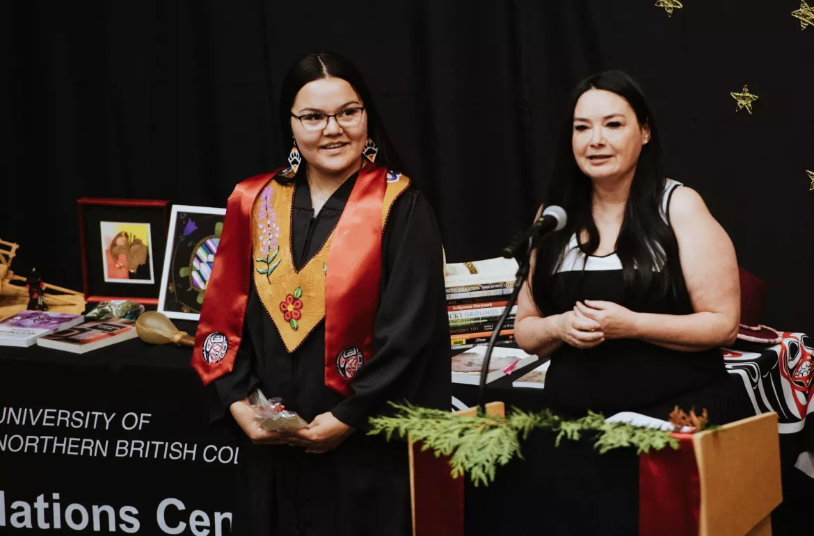 Two people standing at a podium, person on the left