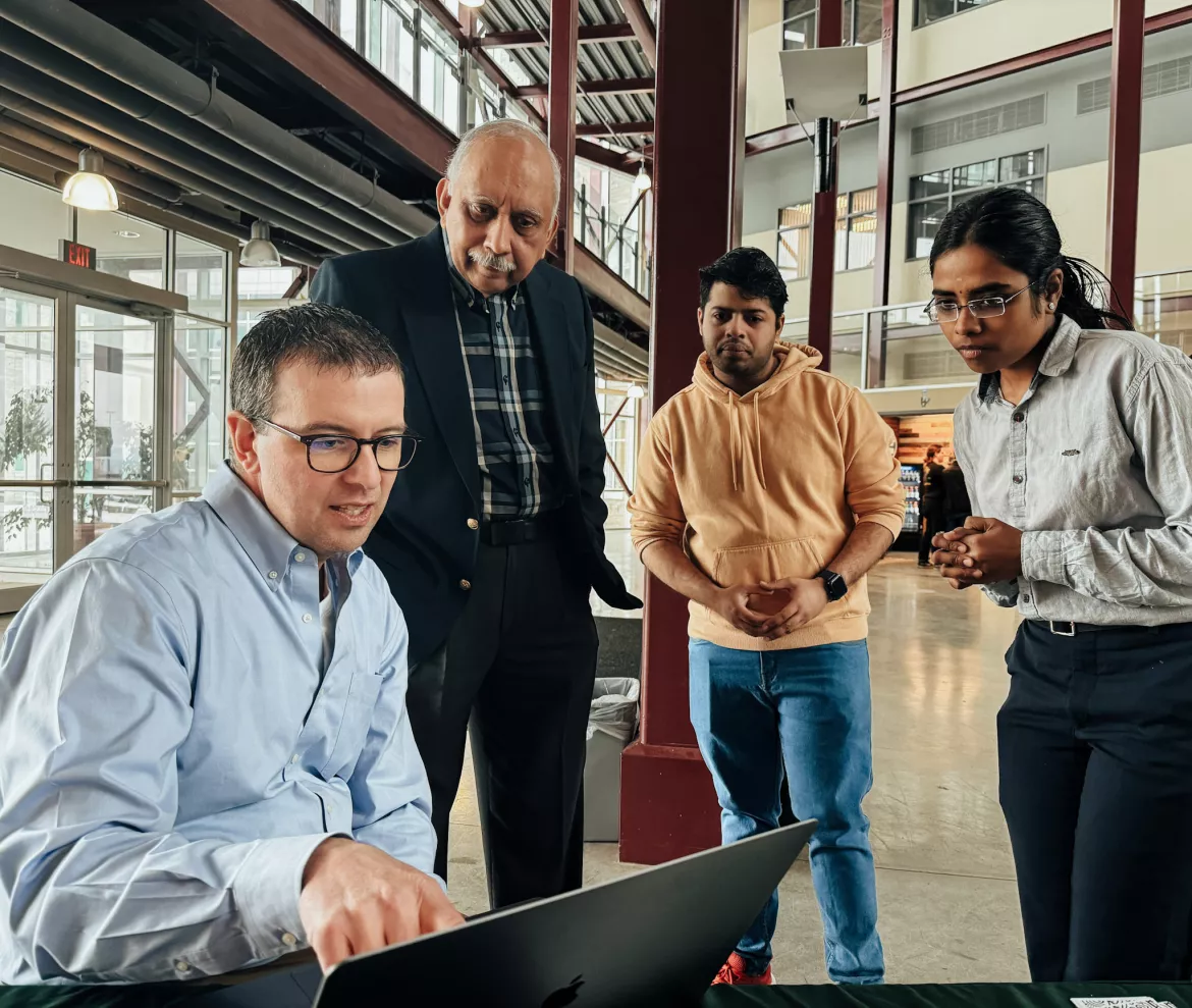 Four people look at a computer screen in the Teaching and Learning atrium at UNBC 