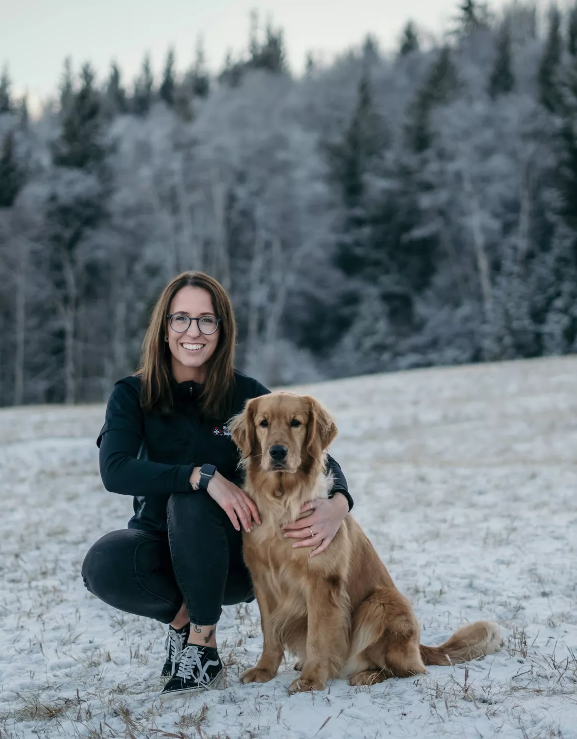 Emily crouching with golden retriever