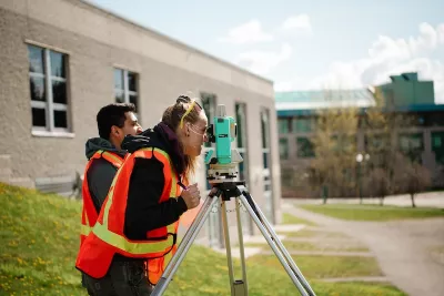 Civil engineering students practise using surveying equipment.