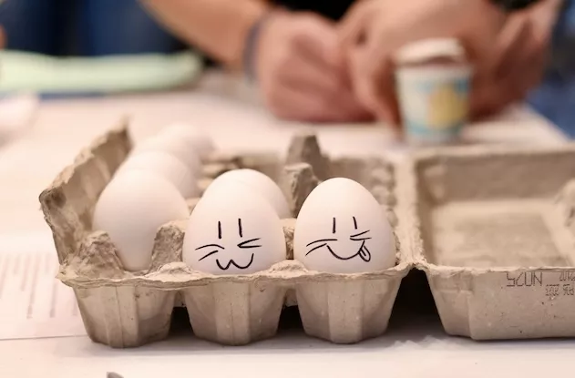 White eggs in a carton with faces drawn on them for an activity.