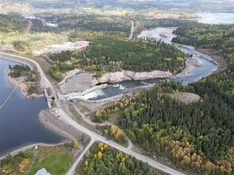 Photo shows aerial shot of forest and river with spillway