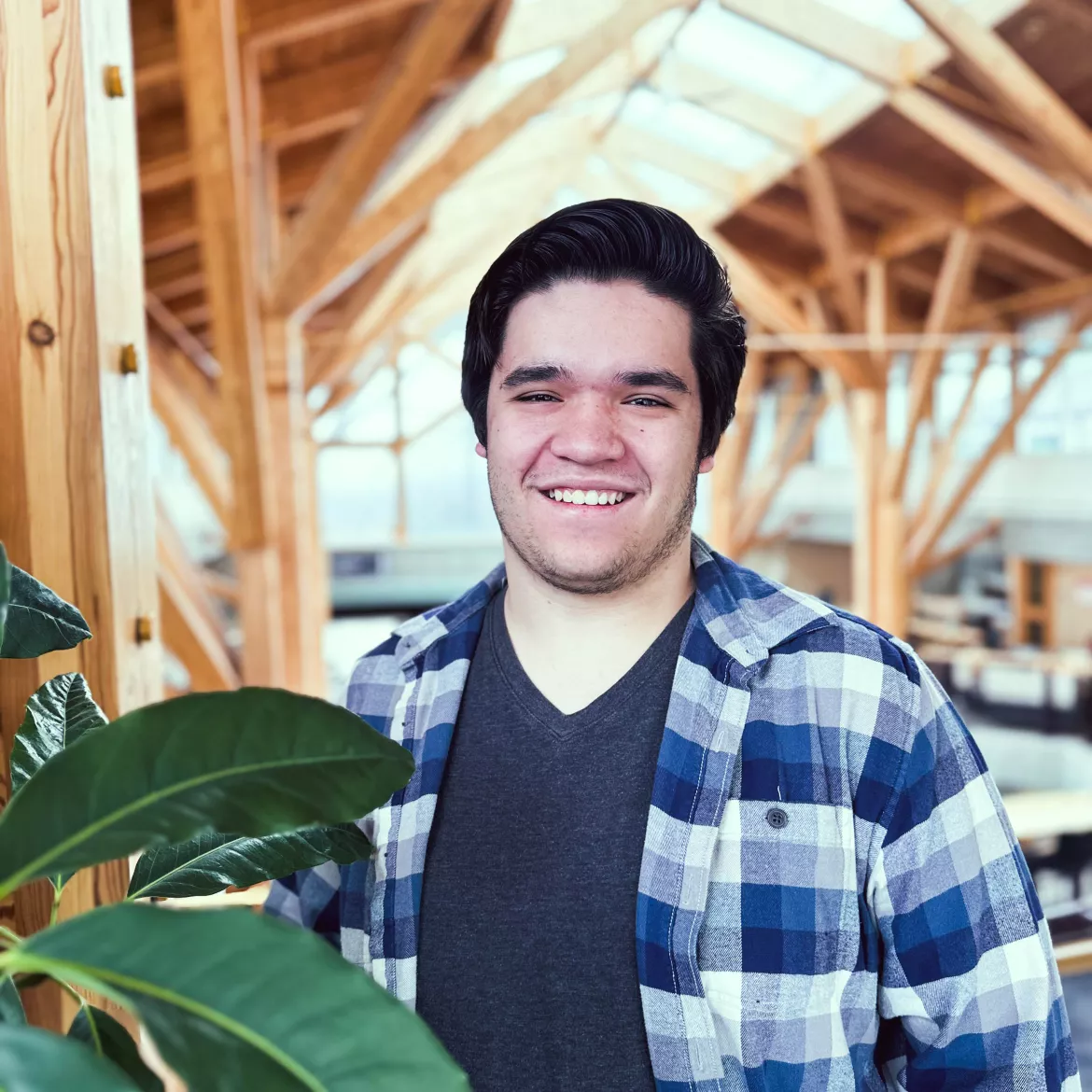 Person in the Canfor Winter Garden at UNBC with plant in the front