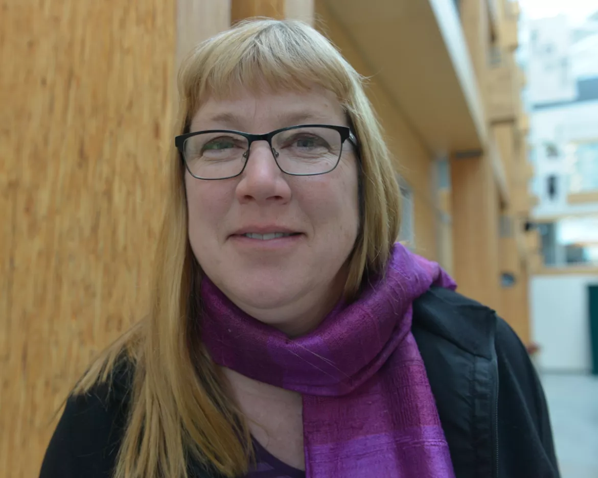 Person wearing glasses, purple scarf and black top.