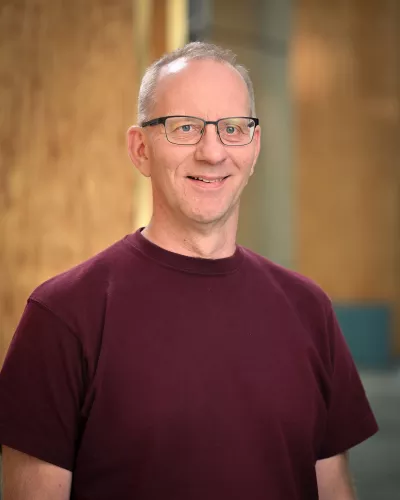 Person wearing glasses and burgundy t-shirt.