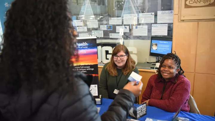 Two people tabling speaking to a student